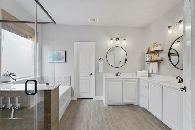 full bath with visible vents, a stall shower, a garden tub, and a sink