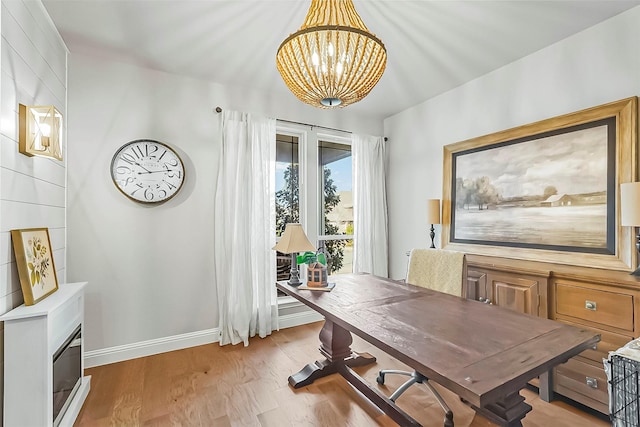 home office with light wood finished floors, an inviting chandelier, and baseboards