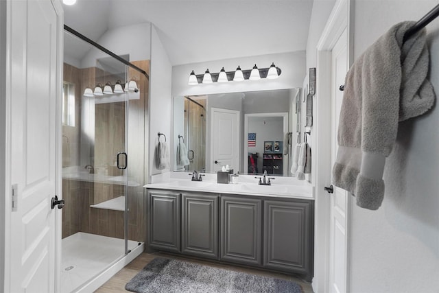 full bathroom with a sink, wood finished floors, a stall shower, and double vanity