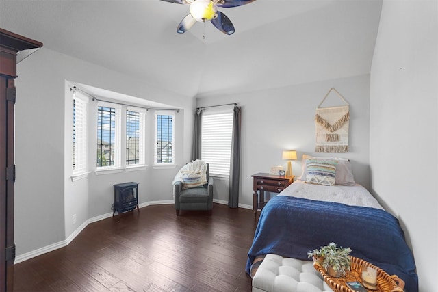 bedroom with ceiling fan, a wood stove, lofted ceiling, and hardwood / wood-style flooring