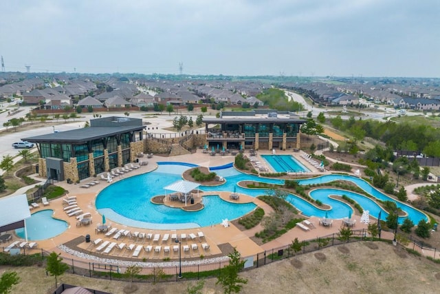 pool with a patio area, fence, a residential view, and a water slide