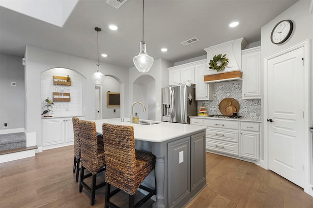 kitchen featuring visible vents, appliances with stainless steel finishes, wood finished floors, arched walkways, and a sink