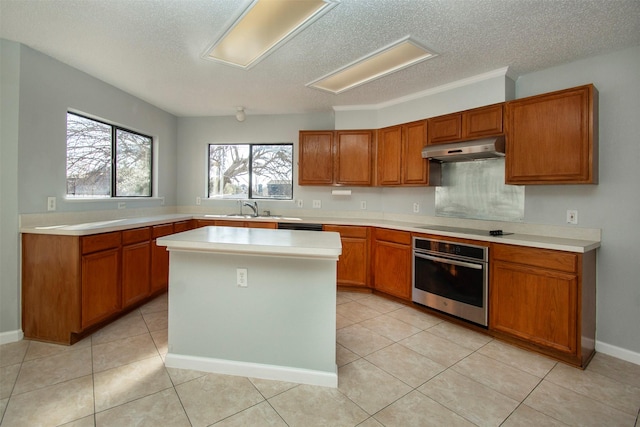 kitchen with oven, black electric cooktop, under cabinet range hood, and brown cabinetry