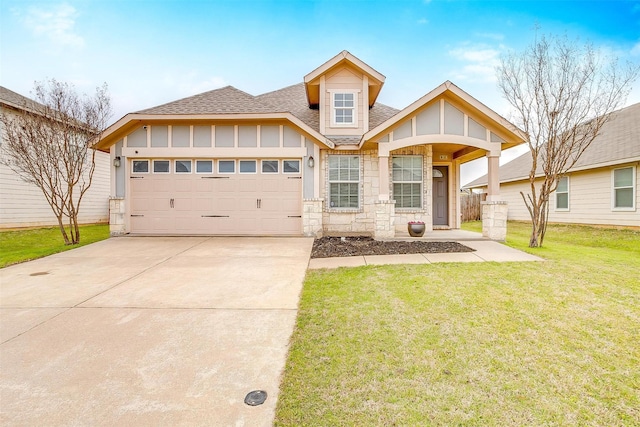 view of front of home featuring a front yard, driveway, a shingled roof, stone siding, and a garage