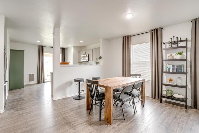 dining space with baseboards, a healthy amount of sunlight, and light wood finished floors