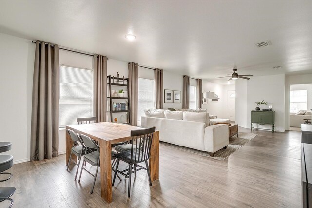 dining room with visible vents, baseboards, wood finished floors, and a ceiling fan