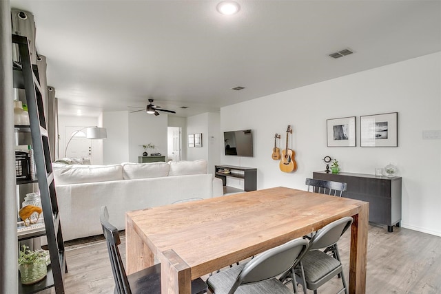 dining area with visible vents, baseboards, light wood-type flooring, and a ceiling fan