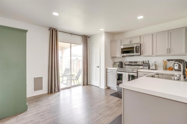 kitchen with light wood-type flooring, light countertops, recessed lighting, stainless steel appliances, and a sink