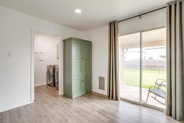 unfurnished bedroom featuring baseboards, light wood finished floors, washing machine and clothes dryer, access to exterior, and a walk in closet