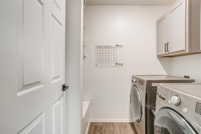 laundry area with washing machine and clothes dryer, cabinet space, light wood finished floors, and baseboards