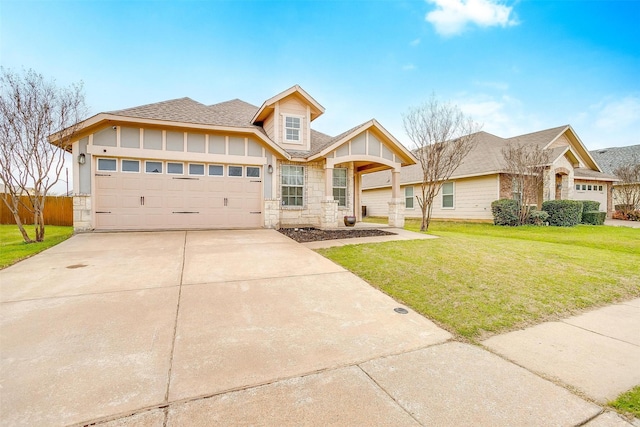 view of front of property with an attached garage, a front yard, roof with shingles, stone siding, and driveway