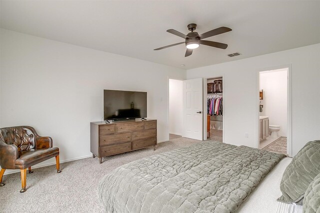 bedroom featuring visible vents, a walk in closet, a closet, baseboards, and light colored carpet