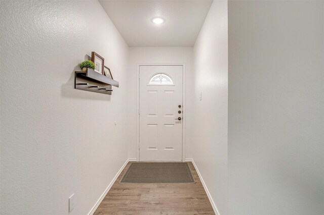 doorway to outside with baseboards and wood finished floors