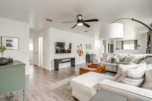 living area featuring visible vents, a ceiling fan, and wood finished floors