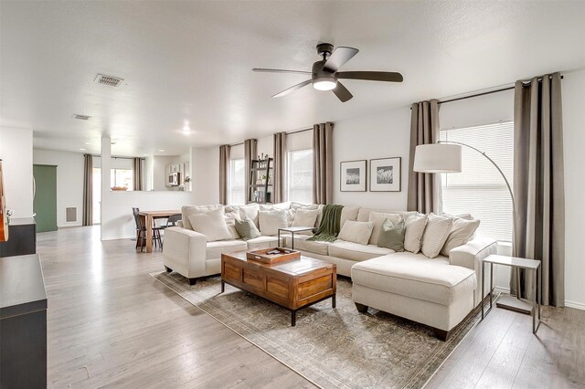 living area featuring ceiling fan, visible vents, and wood finished floors