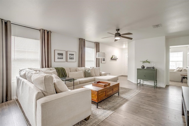 living room featuring ceiling fan, visible vents, and wood finished floors