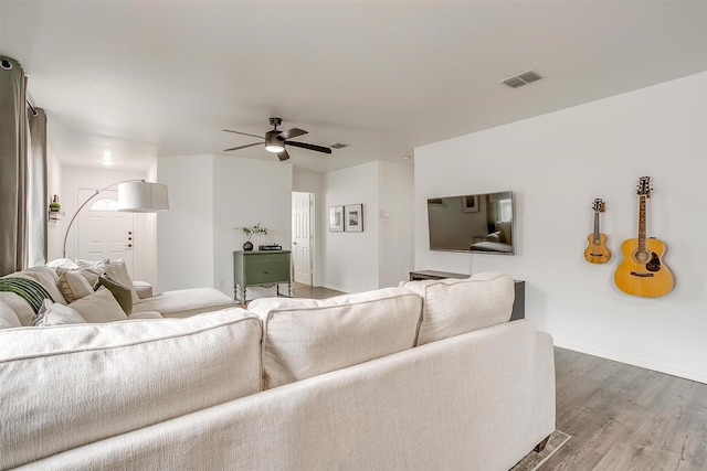 living area featuring ceiling fan, visible vents, baseboards, and wood finished floors