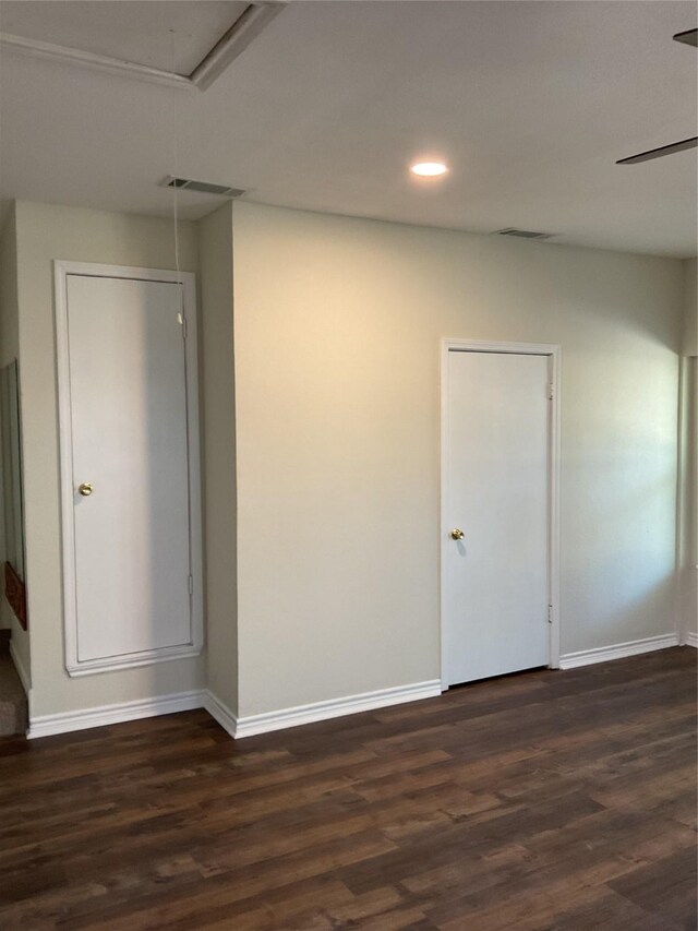 empty room featuring attic access, baseboards, visible vents, and dark wood-type flooring