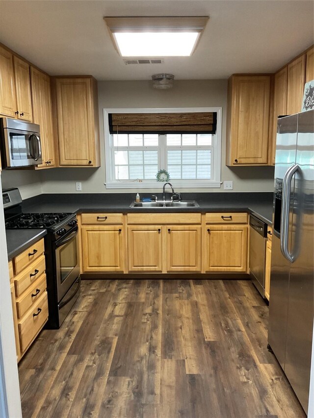 kitchen with visible vents, dark wood-type flooring, a sink, dark countertops, and appliances with stainless steel finishes