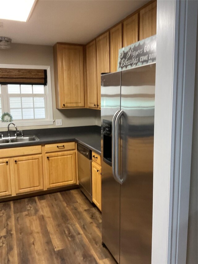 kitchen with dark countertops, appliances with stainless steel finishes, dark wood-type flooring, and a sink