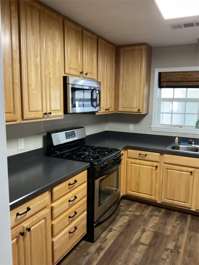 kitchen featuring visible vents, dark wood finished floors, a sink, appliances with stainless steel finishes, and dark countertops