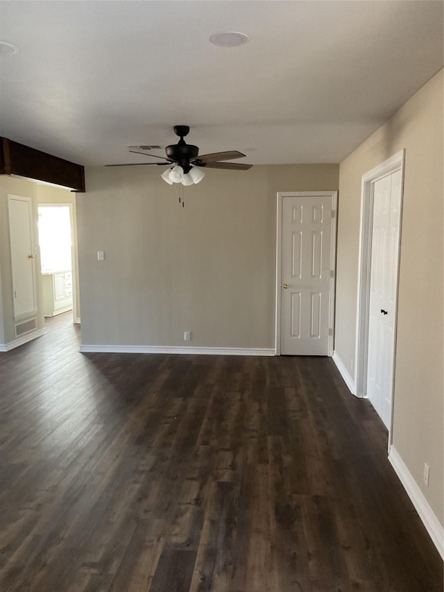 spare room featuring baseboards, dark wood finished floors, and a ceiling fan