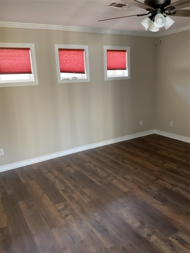 unfurnished room featuring crown molding, baseboards, dark wood-type flooring, and a wealth of natural light