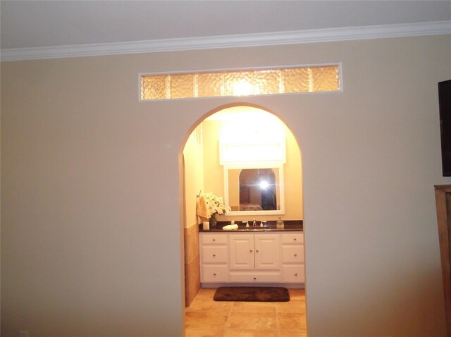 interior space featuring light tile patterned floors, crown molding, and a sink