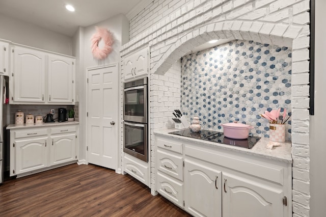 kitchen featuring tasteful backsplash, brick wall, appliances with stainless steel finishes, white cabinets, and dark wood-style flooring