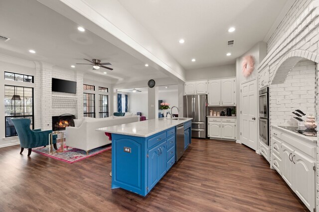 kitchen featuring open floor plan, appliances with stainless steel finishes, blue cabinets, and a sink