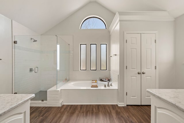 bathroom featuring vaulted ceiling, a stall shower, wood finished floors, a bath, and vanity