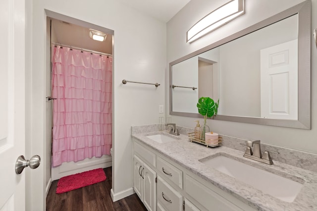 bathroom featuring double vanity, toilet, wood finished floors, and a sink