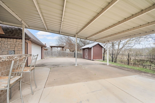 view of patio featuring a storage shed, an outdoor structure, a fenced backyard, and a garage