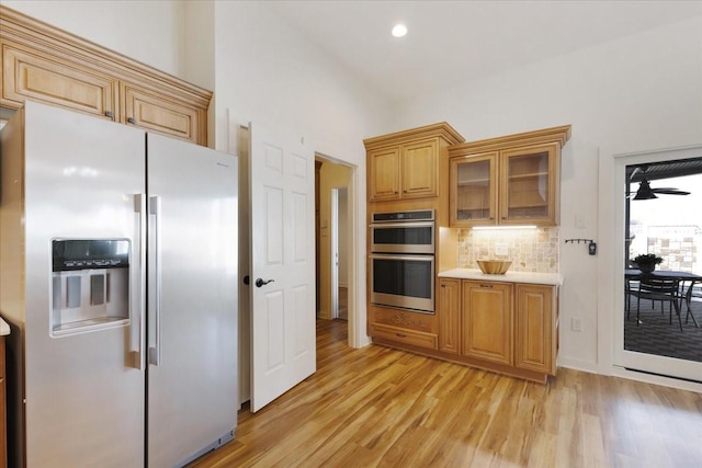 kitchen featuring decorative backsplash, light countertops, light wood-style floors, and stainless steel appliances