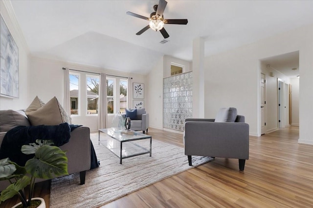 living room featuring light wood finished floors, visible vents, baseboards, vaulted ceiling, and a ceiling fan