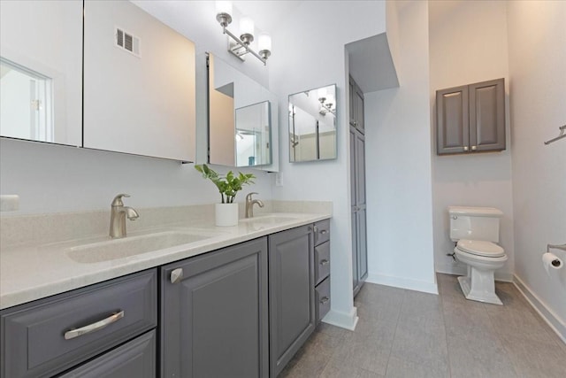 bathroom with a sink, visible vents, toilet, and double vanity