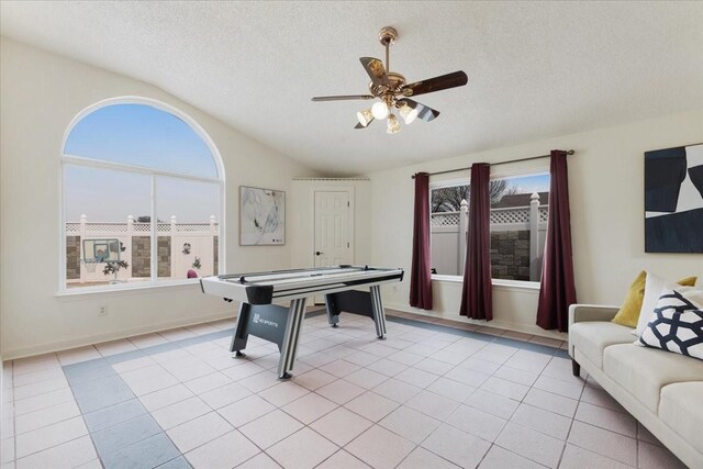 recreation room with light tile patterned floors, lofted ceiling, a textured ceiling, and a ceiling fan