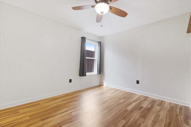 spare room with baseboards, light wood-type flooring, and ceiling fan