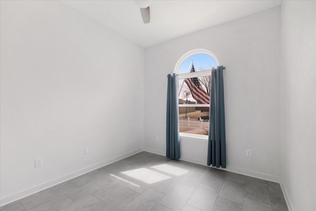 spare room with a ceiling fan and baseboards