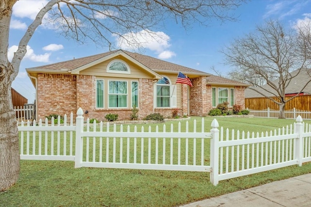 view of front of house featuring brick siding, a fenced front yard, a shingled roof, and a front yard