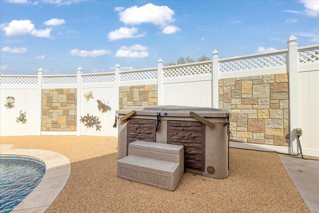 view of patio with a jacuzzi and fence