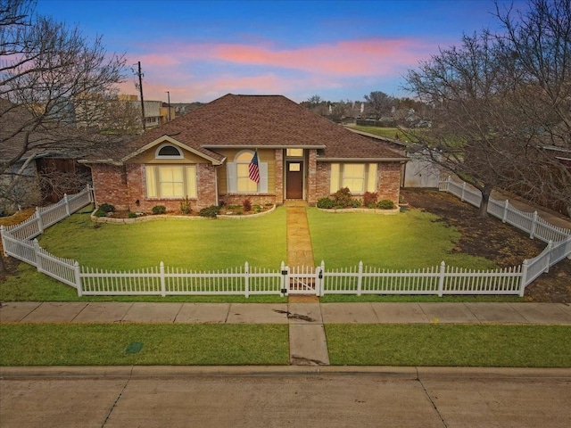 single story home featuring a fenced front yard, brick siding, and a front lawn