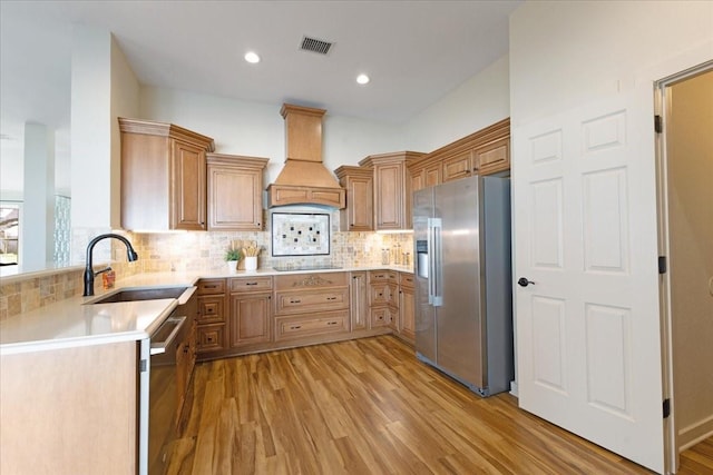 kitchen featuring visible vents, a sink, stainless steel appliances, custom range hood, and light wood-type flooring