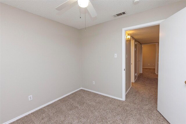 spare room featuring baseboards, visible vents, ceiling fan, a textured ceiling, and light colored carpet