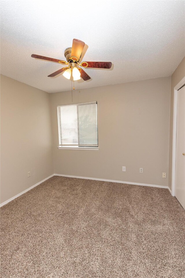 carpeted empty room with baseboards, a textured ceiling, and a ceiling fan