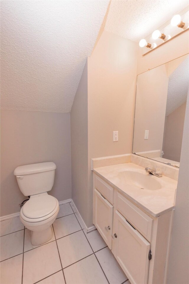 half bath featuring vanity, baseboards, a textured ceiling, tile patterned floors, and toilet