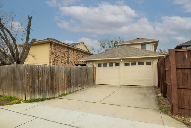 garage featuring concrete driveway and fence