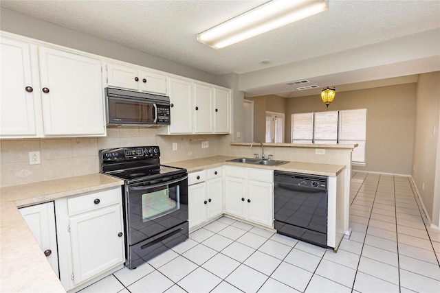 kitchen with a sink, black appliances, white cabinets, and light countertops