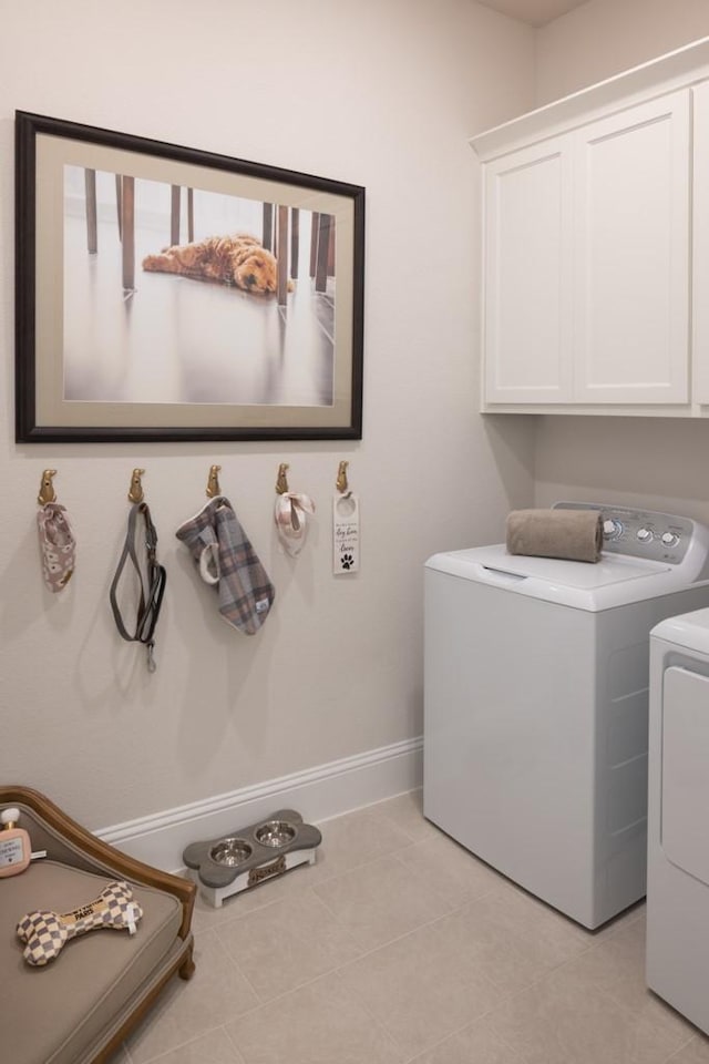 clothes washing area with washer and dryer, baseboards, cabinet space, and light tile patterned floors