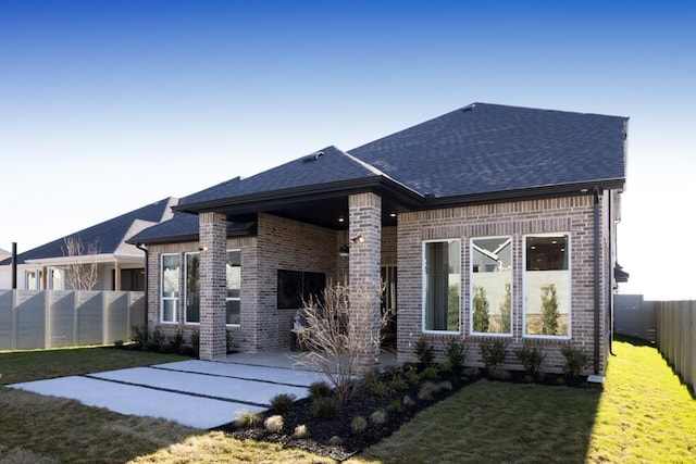 back of property featuring a yard, a patio, brick siding, and a fenced backyard